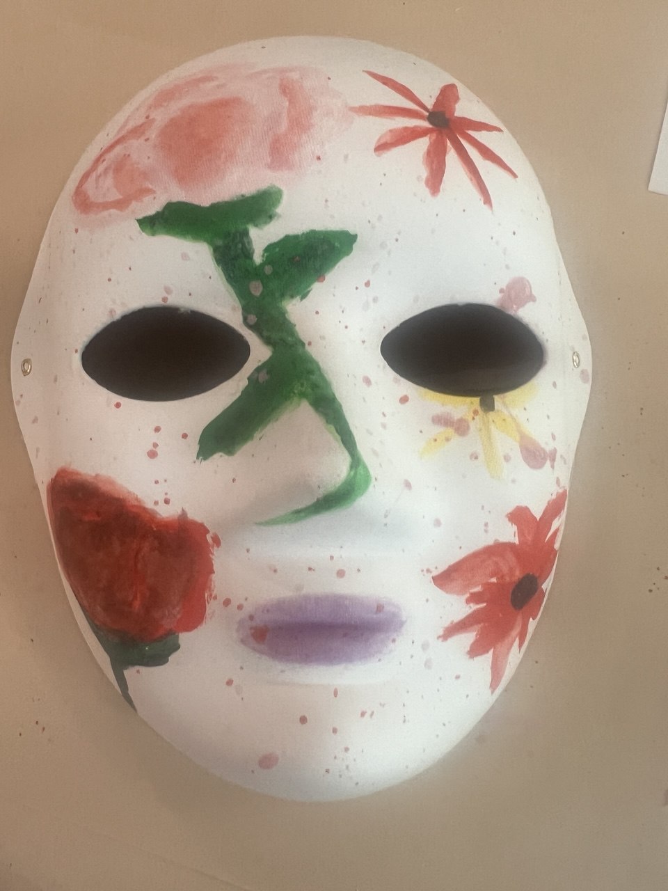 A hand-painted mask decorated with flowers and symbols